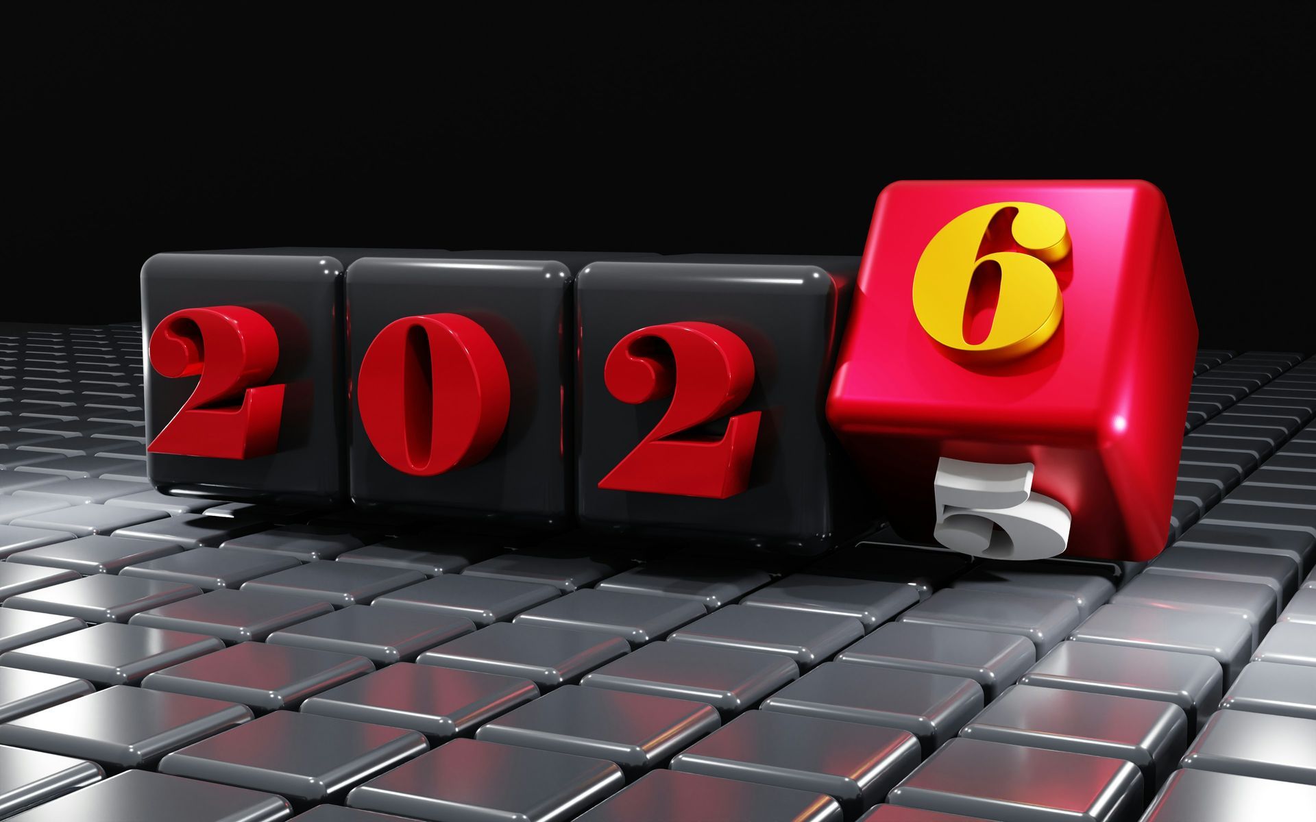 2025 turning to 2026. Cubes with red numbers, the last cube red with the number 6, on a silver tile surface.