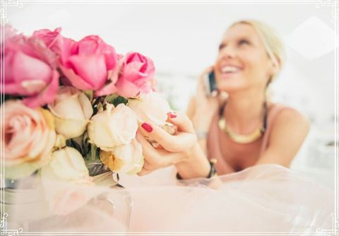 A woman is holding a bouquet of flowers while talking on a cell phone.