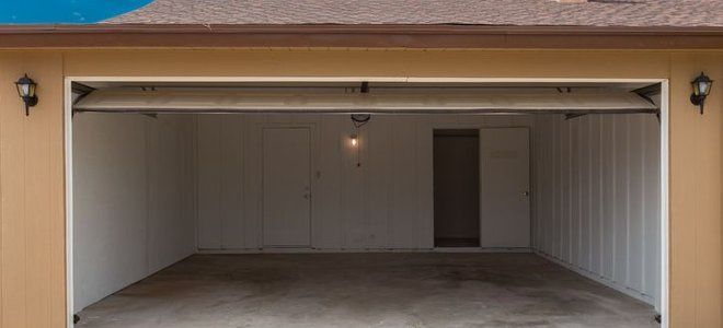 An empty garage with the door open and a doorway.