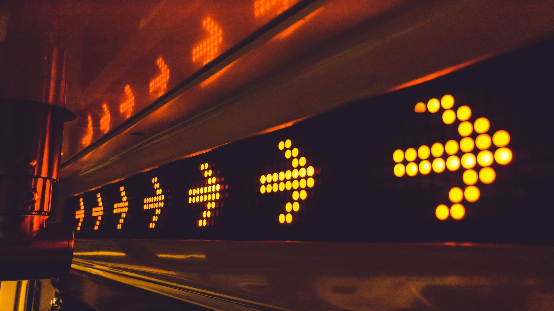 A led light sign with arrows pointing in different directions is lit up at night.