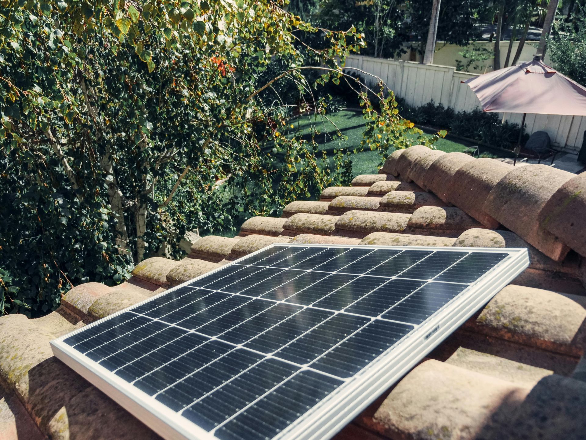 A solar panel is sitting on top of a tiled roof.