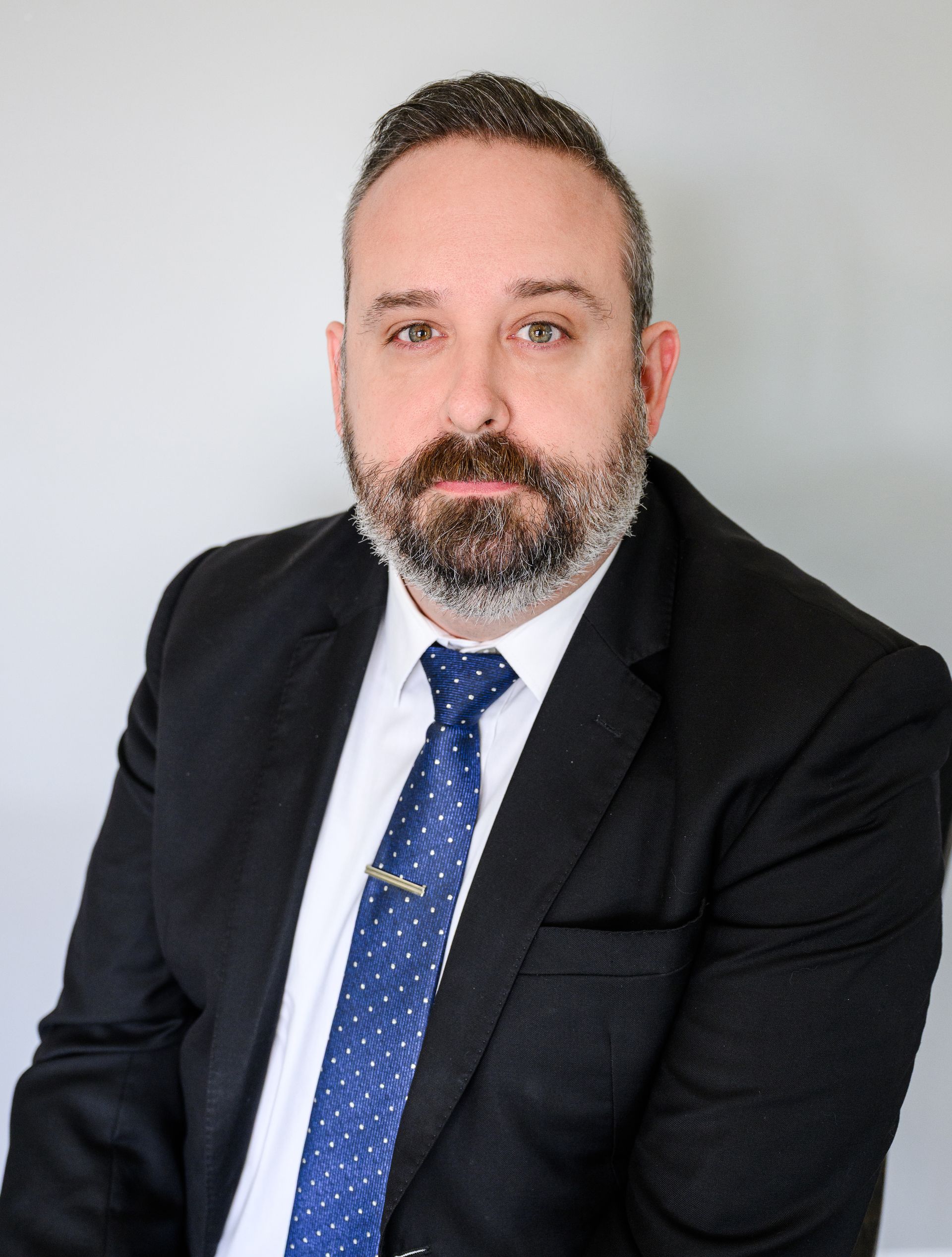 Family of six smiling, sitting on a bench outdoors. Two girls with bows, two boys, and parents.