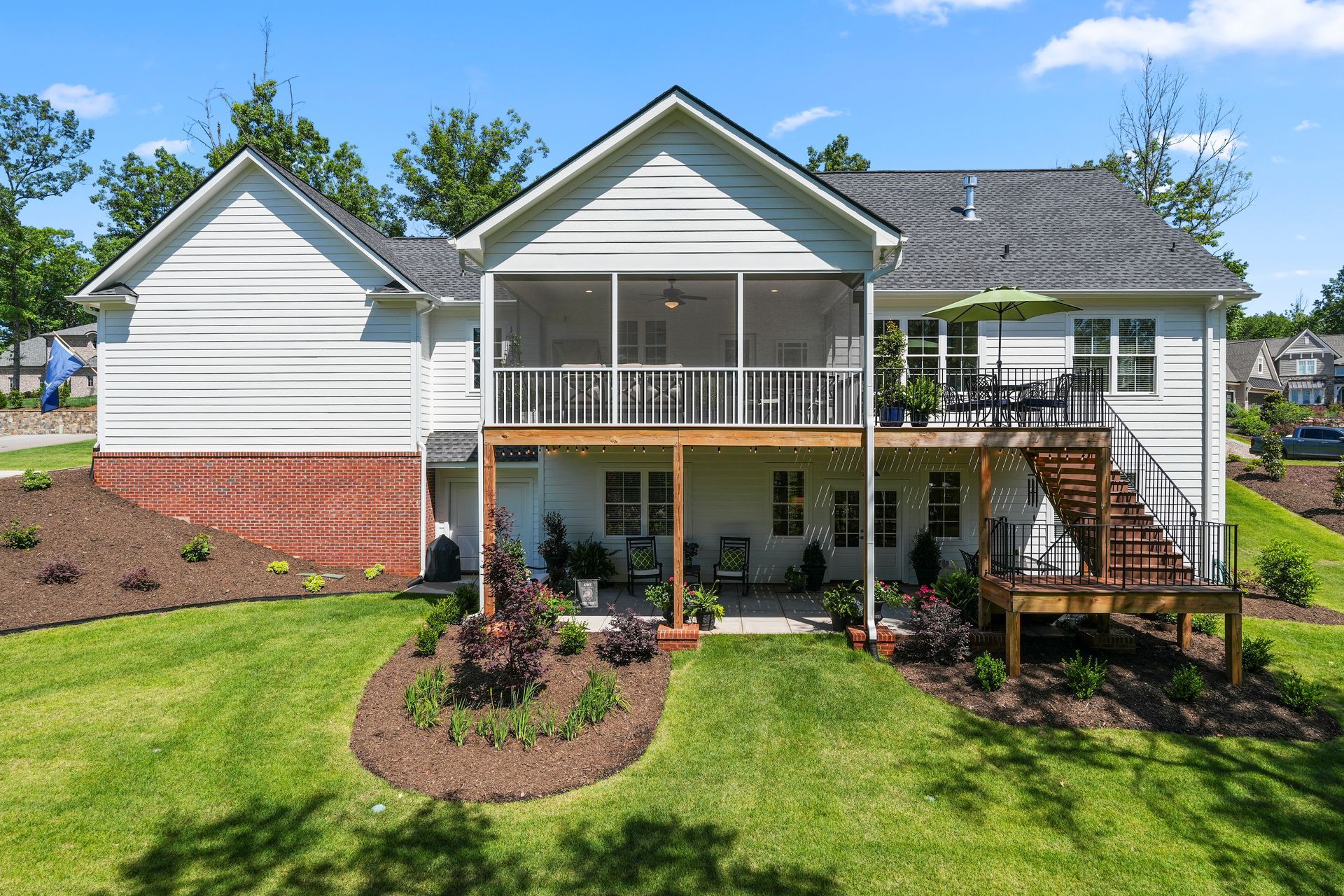 A large white house with a screened in porch and a large deck.