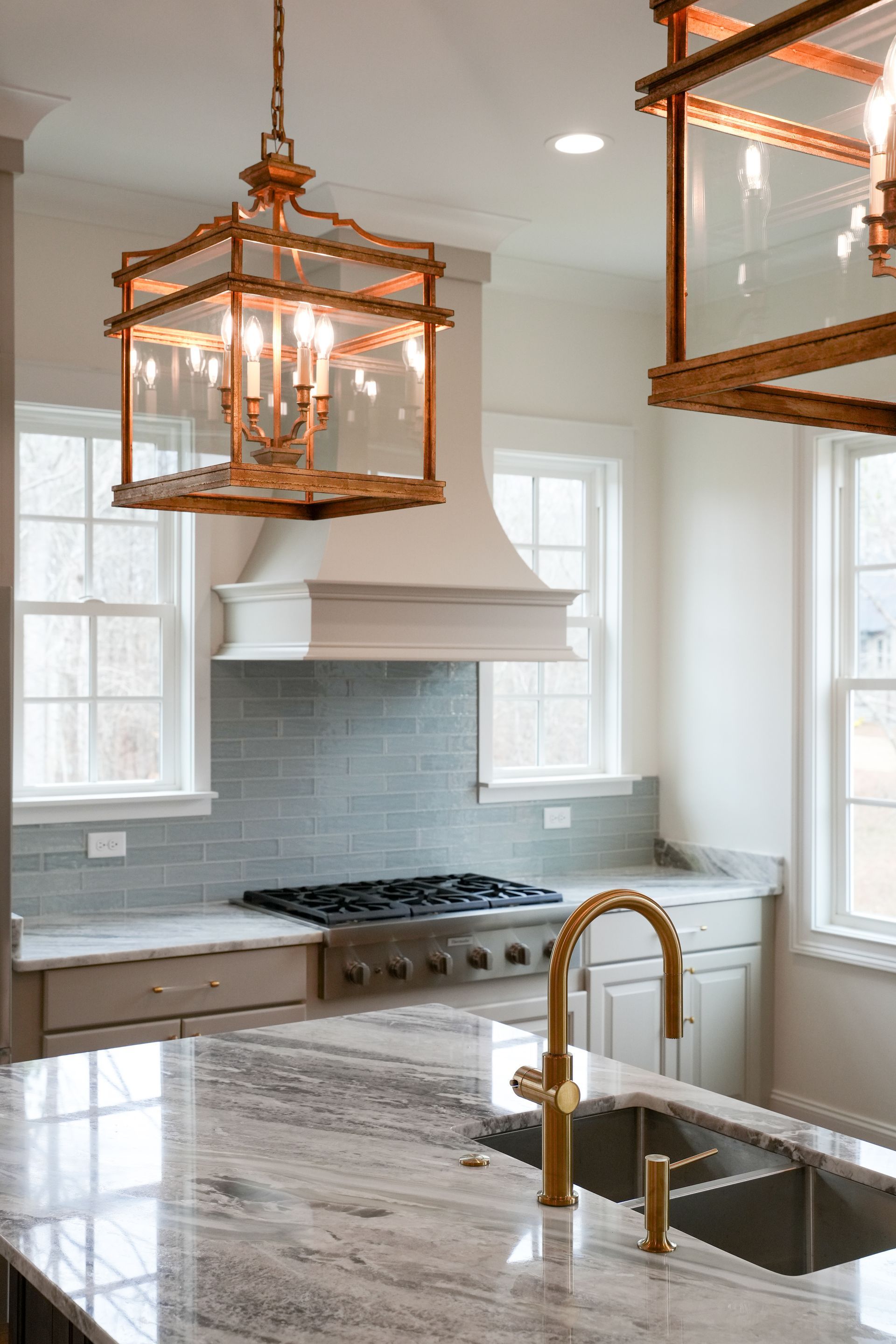 A kitchen with a sink , stove , and lanterns hanging from the ceiling.