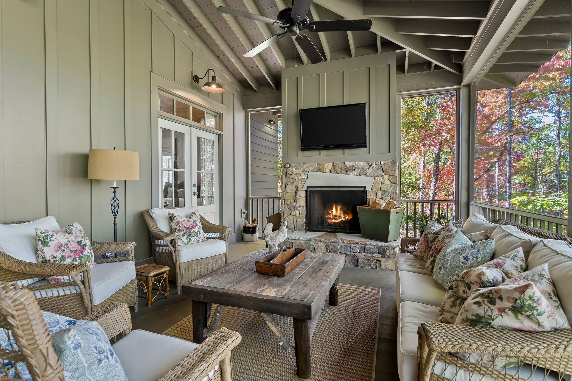 A living room with wicker furniture , a fireplace and a flat screen tv.