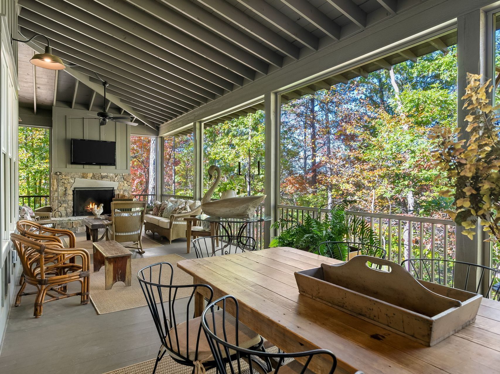 A screened in porch with a table and chairs and a fireplace.