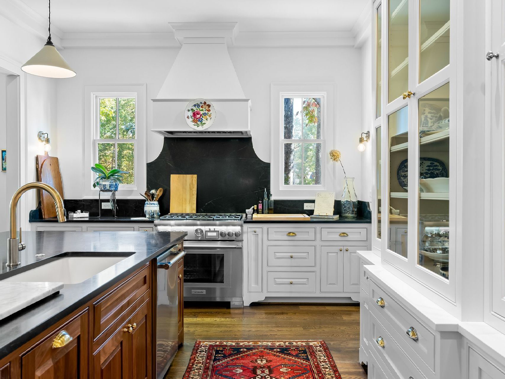 A kitchen with white cabinets , stainless steel appliances , a sink , and a rug.