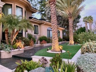 A lush, green garden with pink flowers in front of a building.