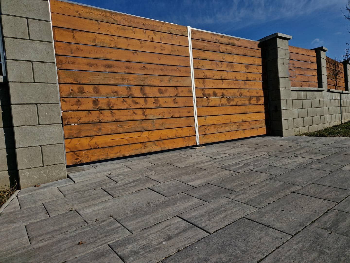 A wooden fence with a brick wall behind it