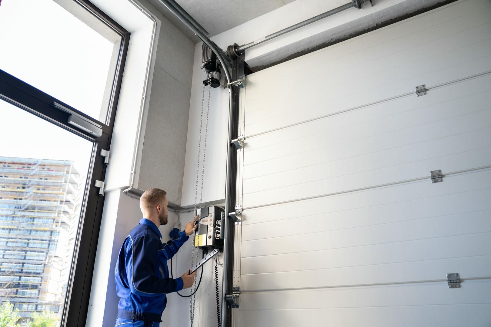 A man is working on a garage door in a garage.