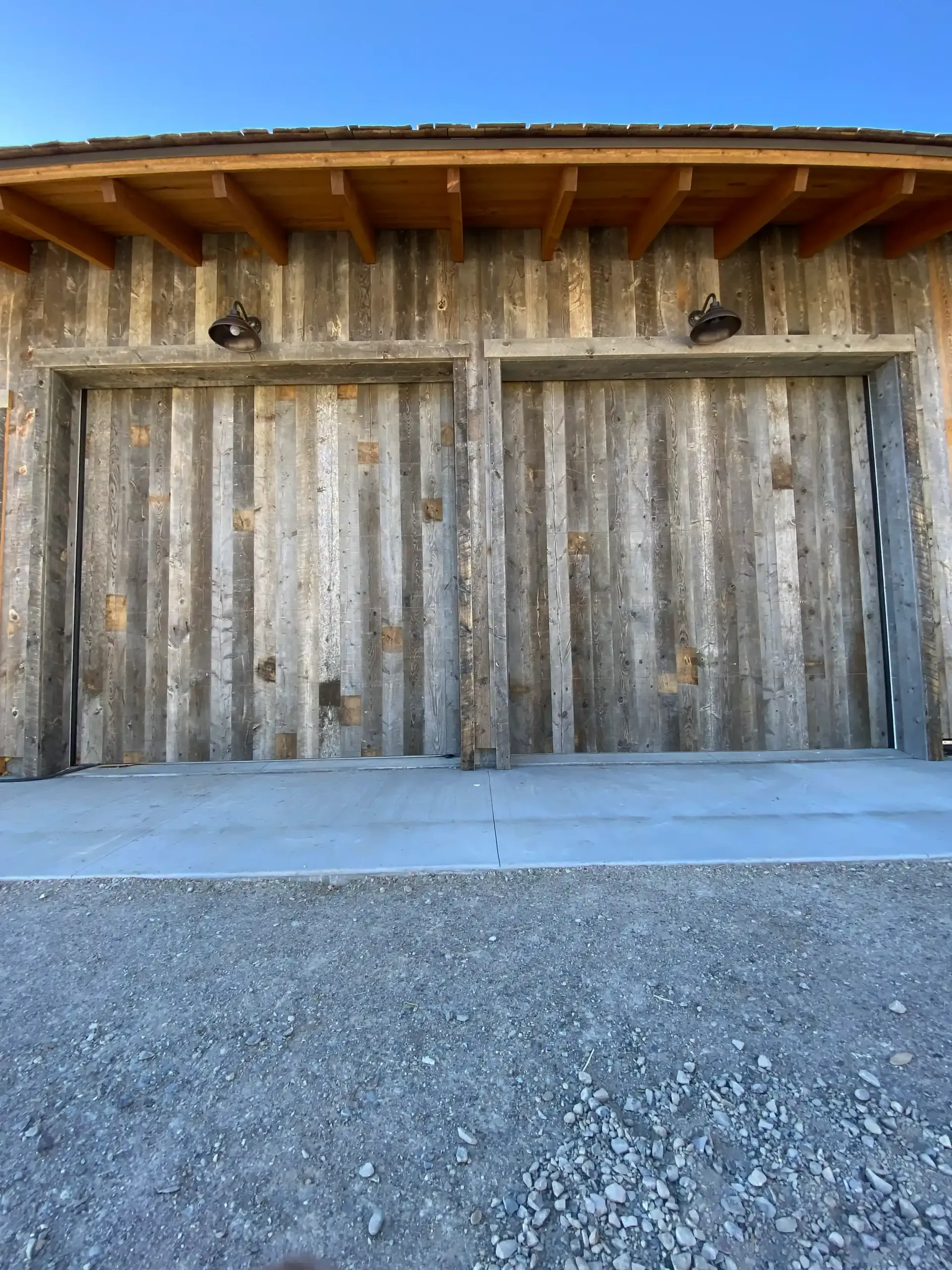 A wooden garage door with a concrete driveway in front of it.