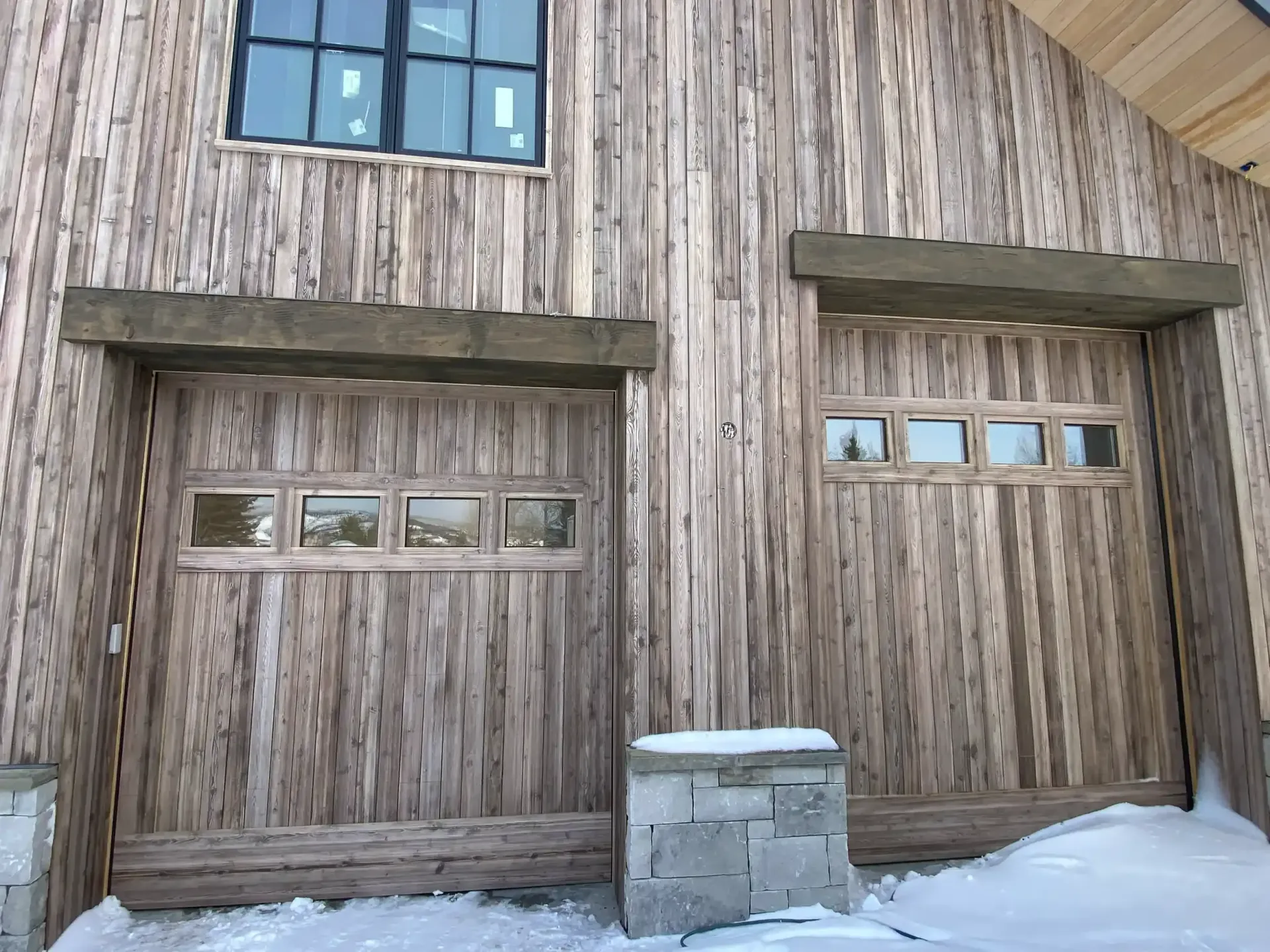 A wooden building with a garage door and a window.