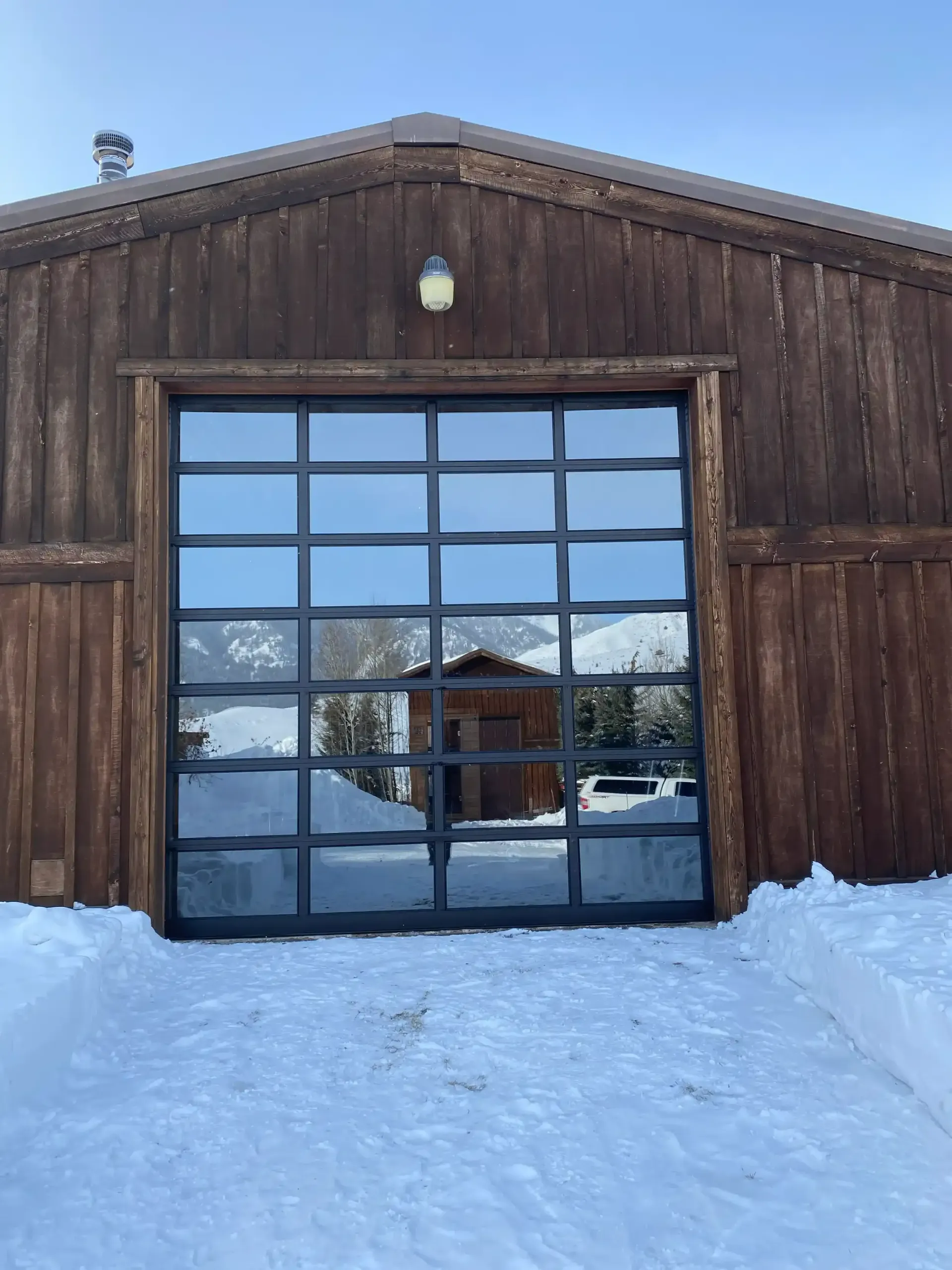 A barn with a large garage door is covered in snow.