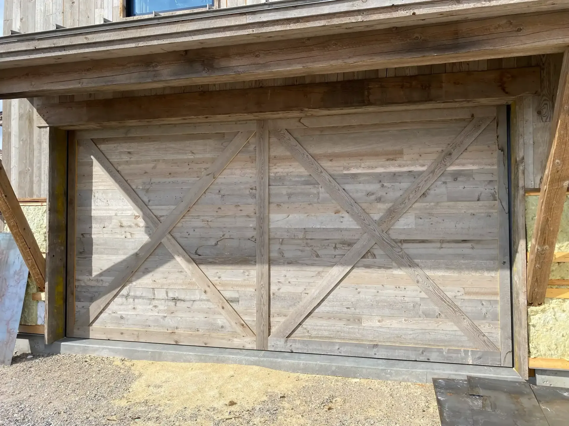 A wooden garage door is being built on the side of a house.