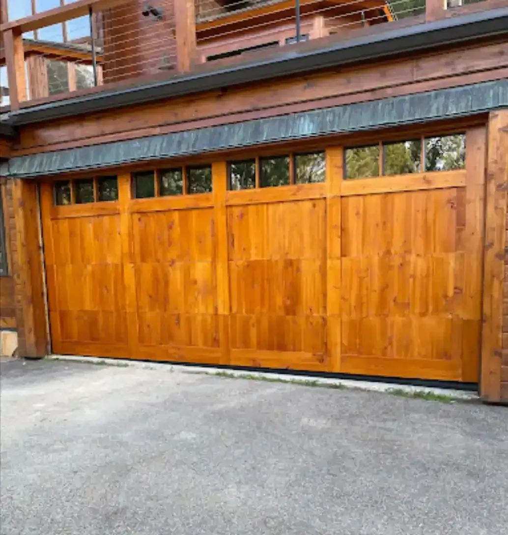 A wooden garage door is sitting in front of a house.