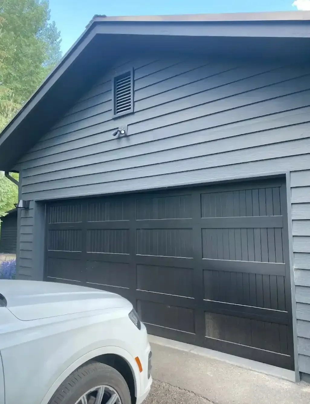 A white car is parked in front of a garage door.