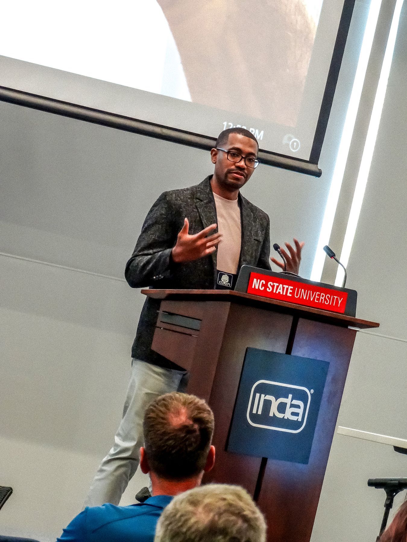 Man in blazer speaks at a podium with 