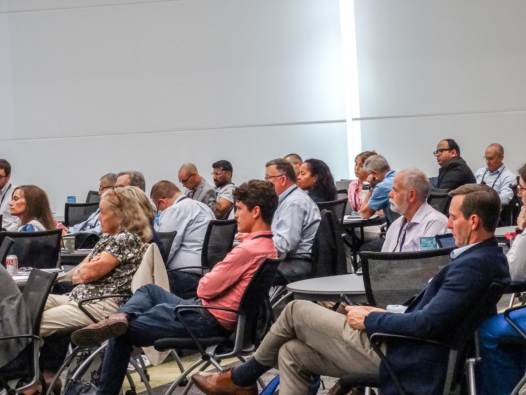 People seated in a conference room, listening to a presentation.
