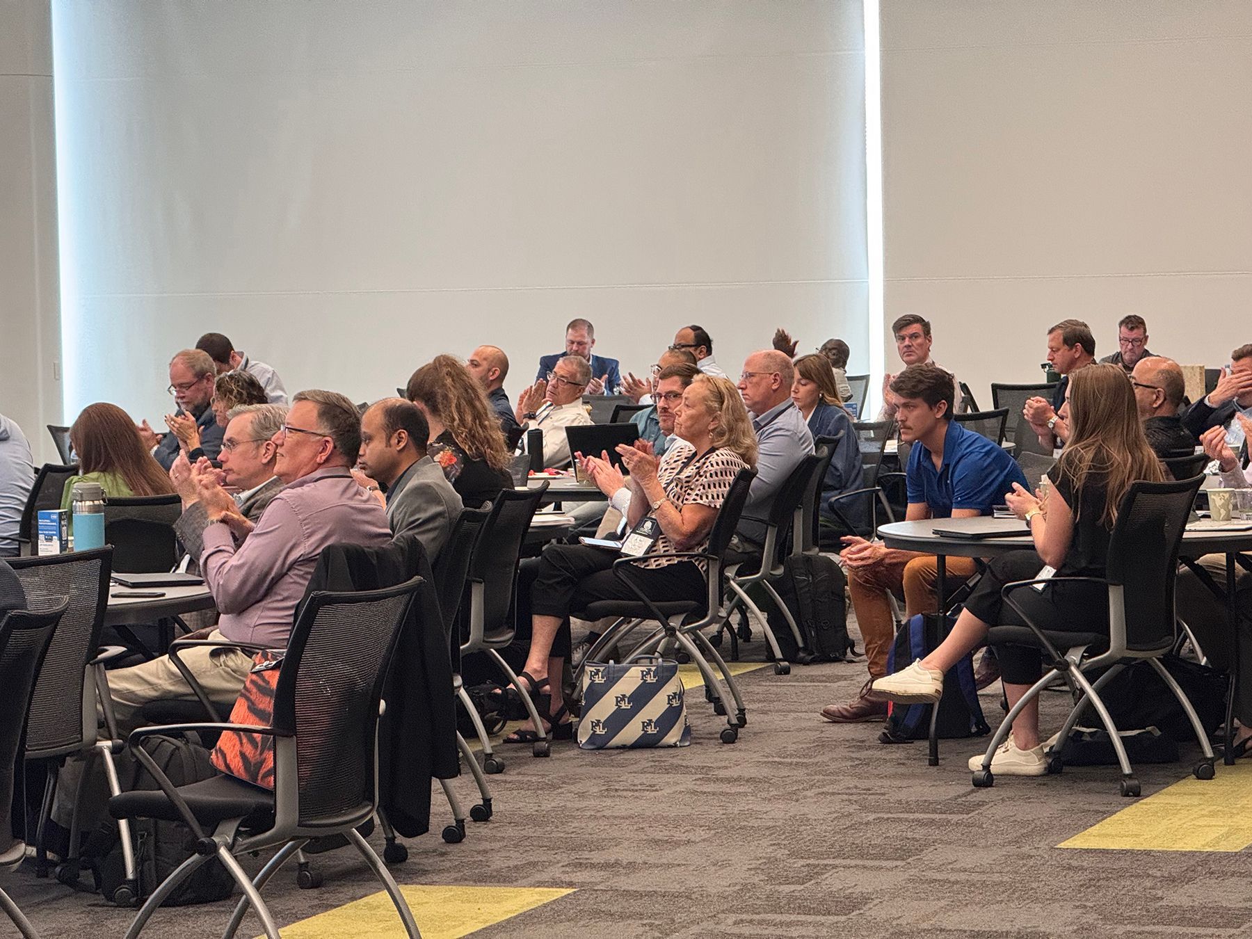 People clapping in a conference room. Attendees in business attire.