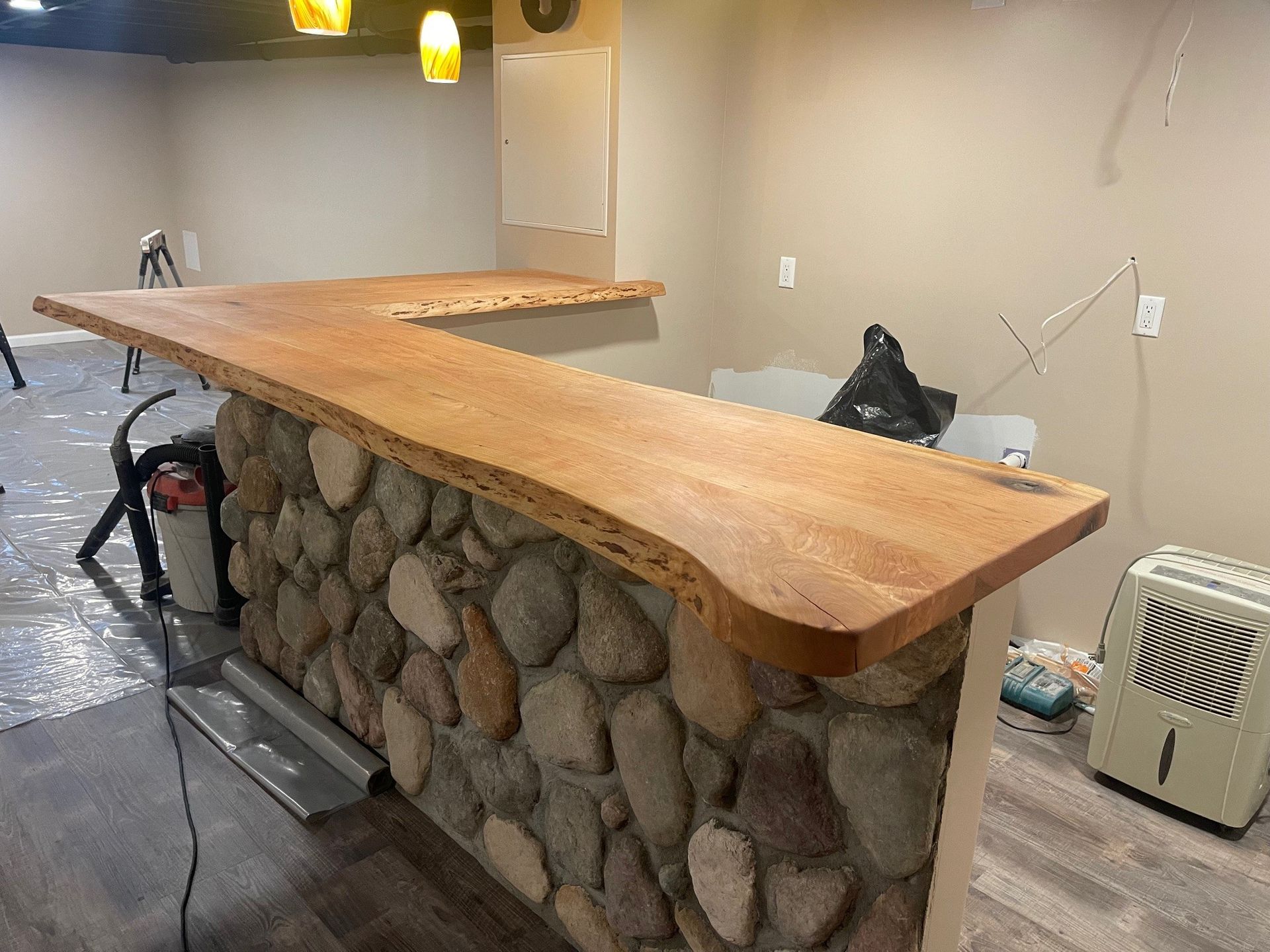 A wooden counter top is sitting next to a stone wall in a room.