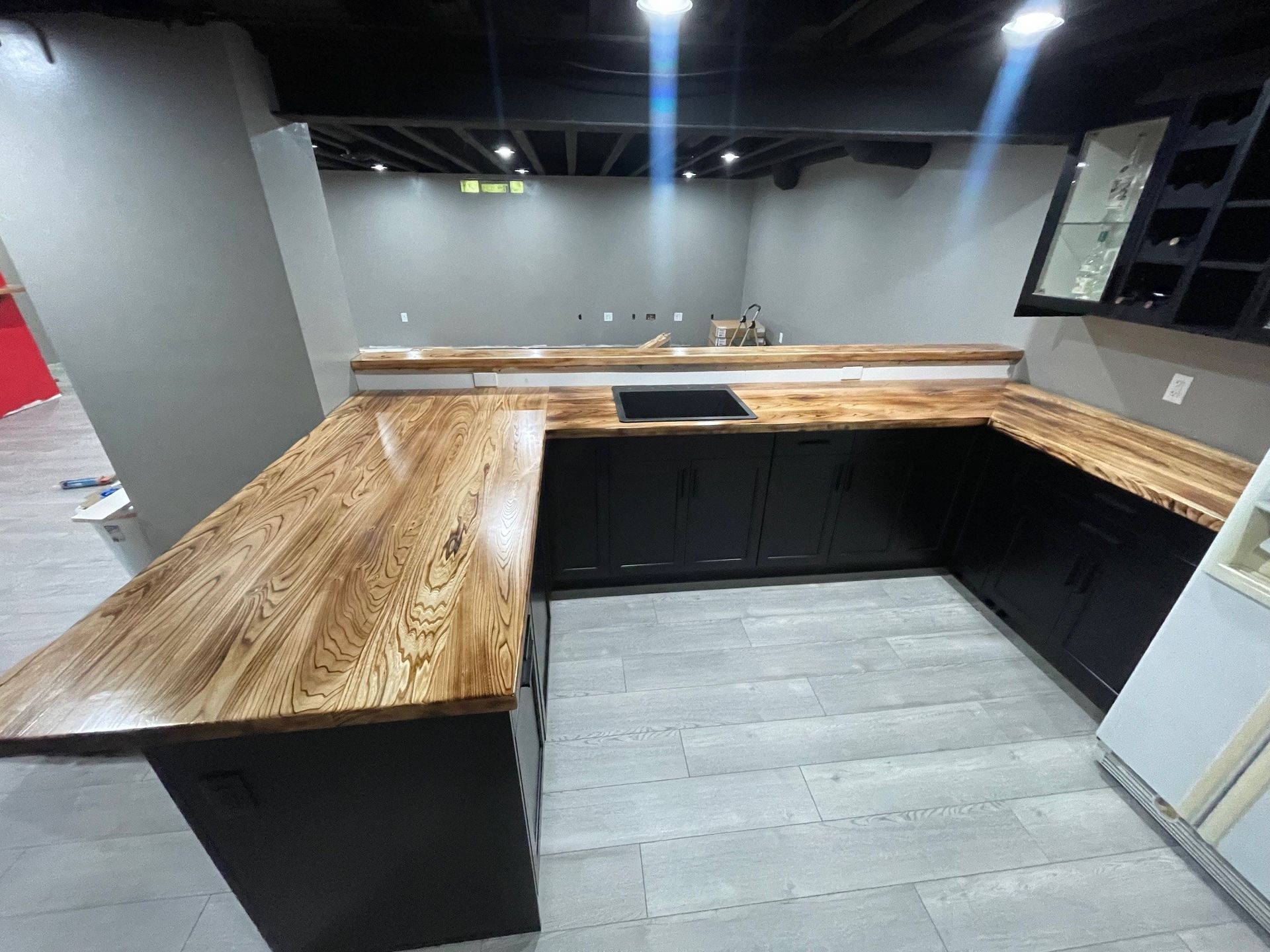 A kitchen with a wooden counter top and black cabinets