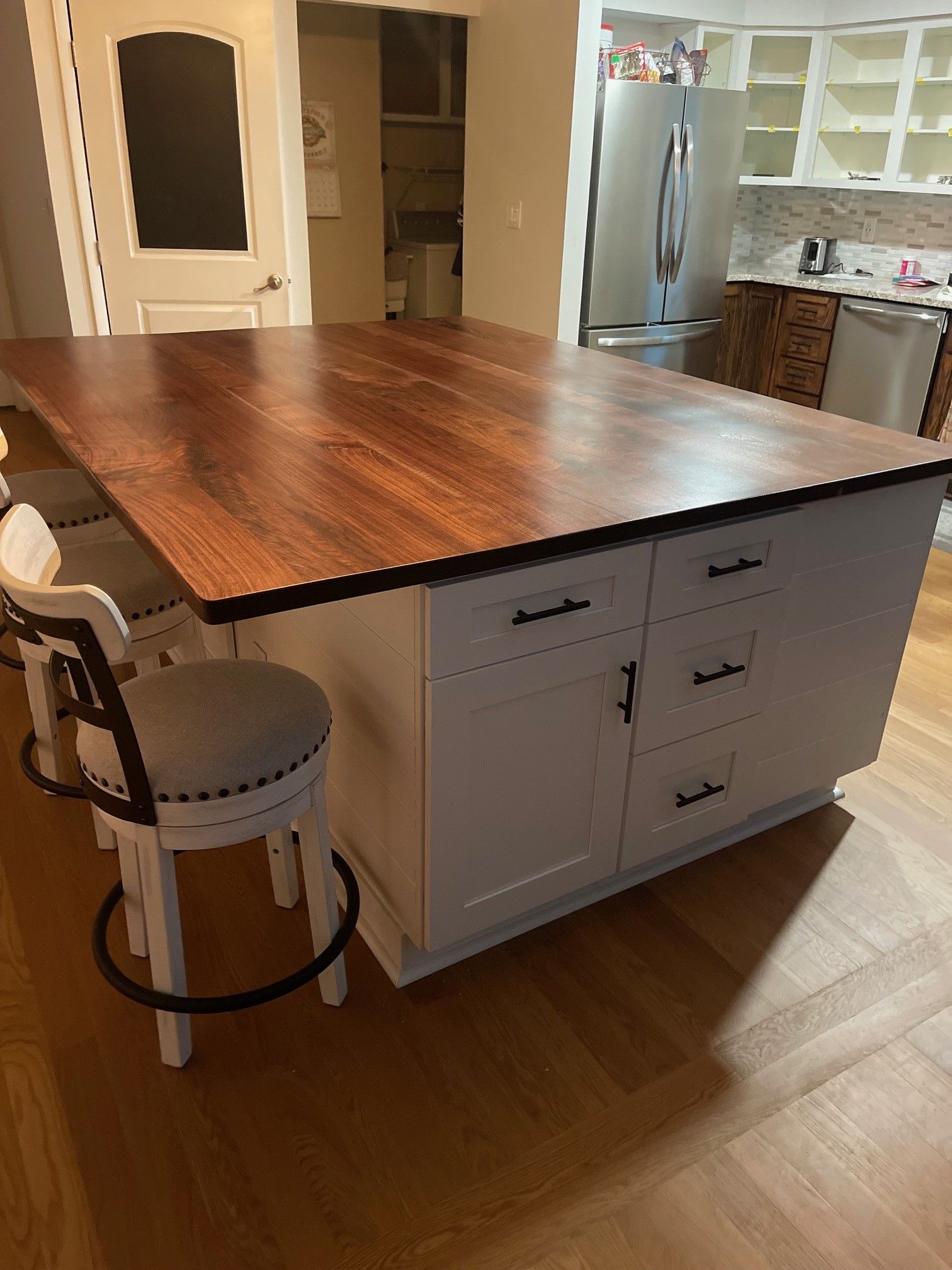 A kitchen island with a wooden top and two chairs.