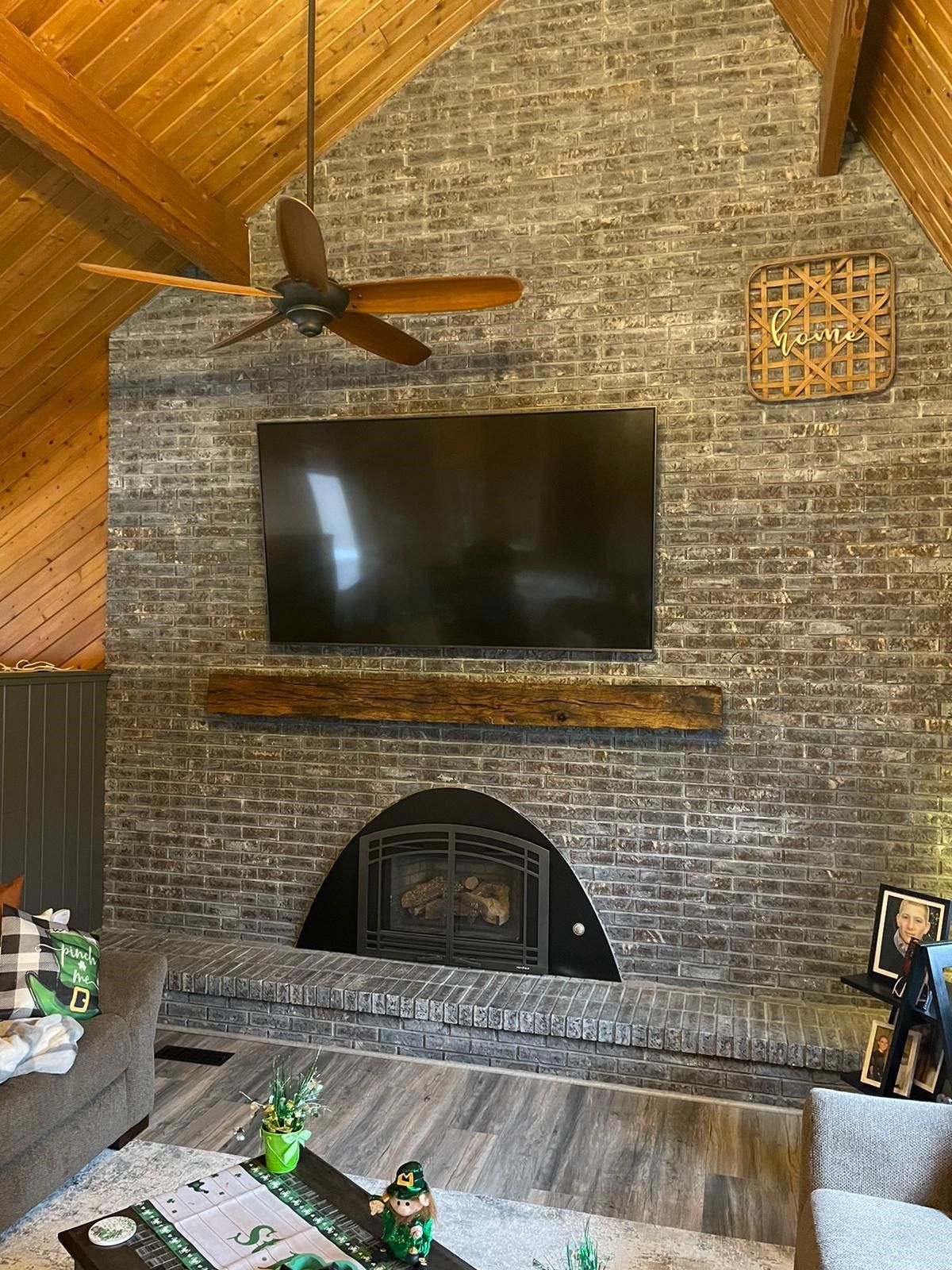 A living room with a fireplace , television , and ceiling fan.