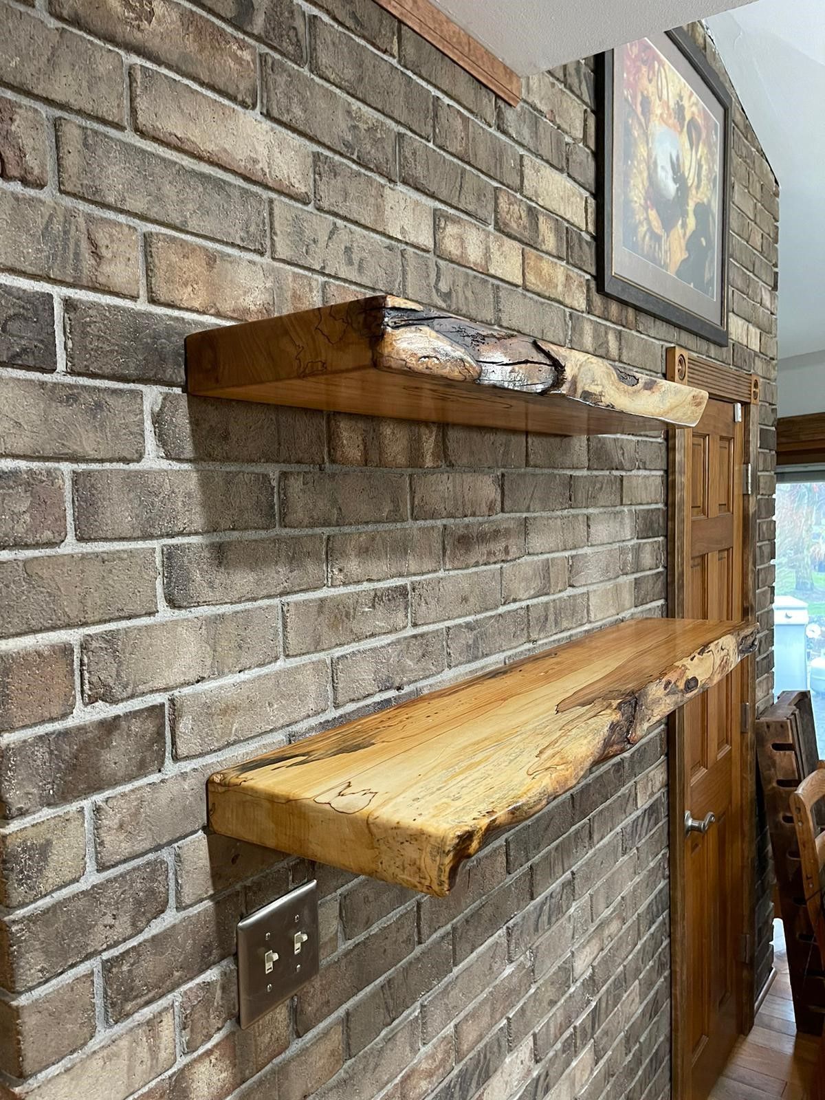 Two wooden shelves are hanging on a brick wall.