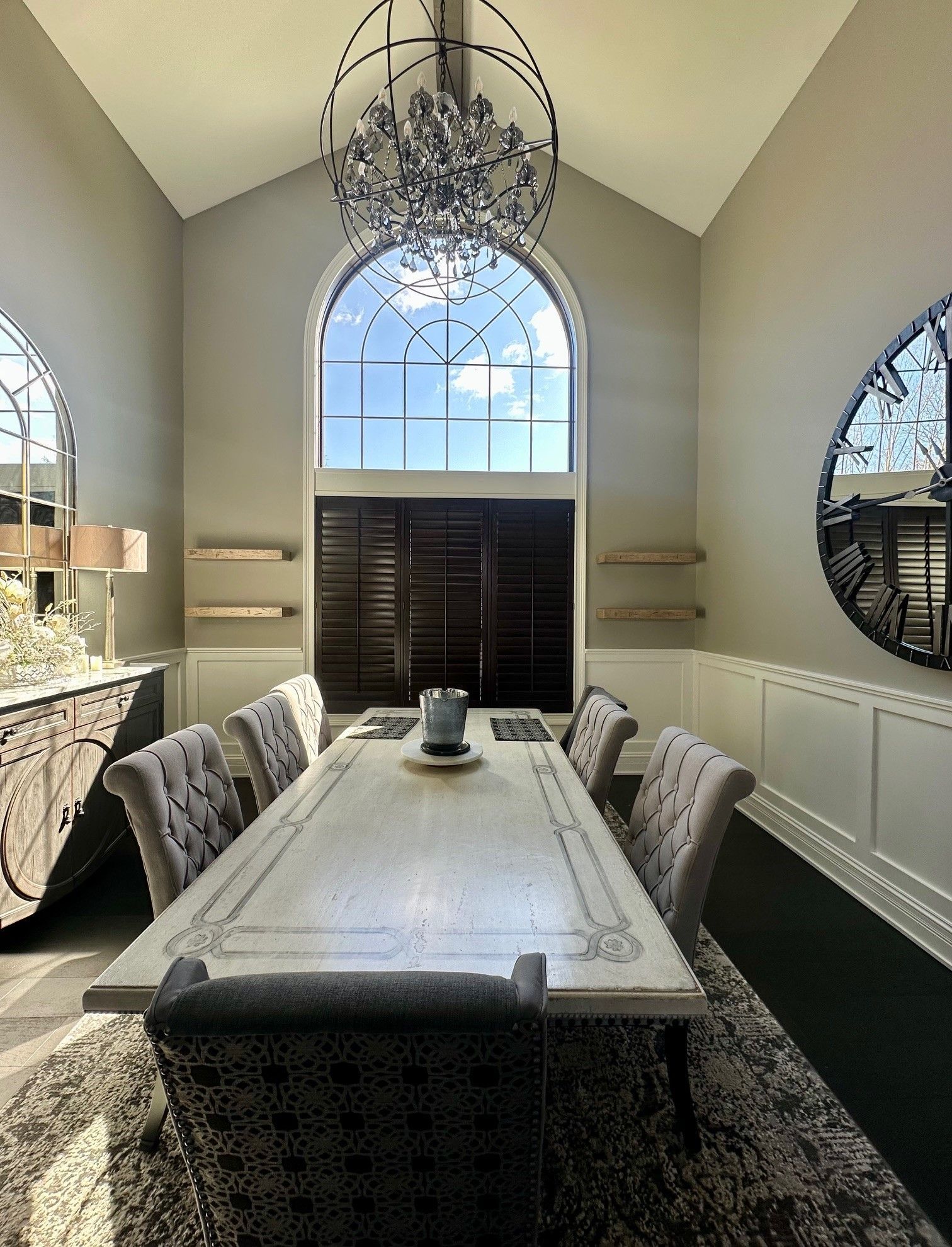 A dining room with a long table and chairs and a chandelier hanging from the ceiling.