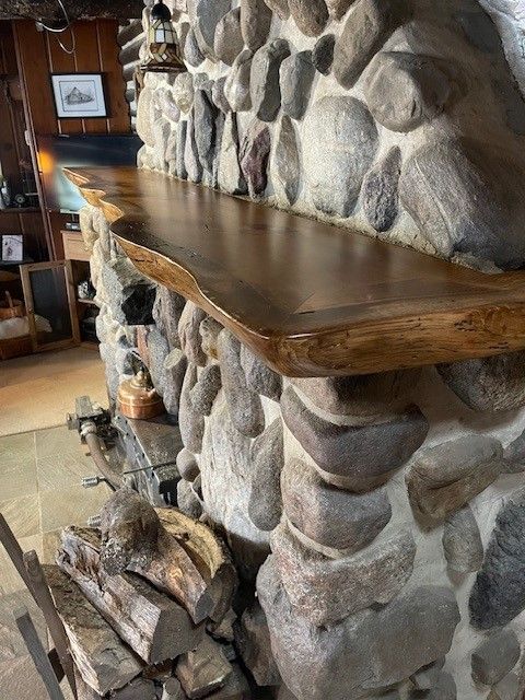A wooden shelf is sitting in front of a stone wall.