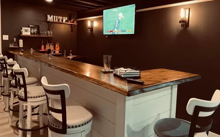 A bar with stools and a television on the wall.