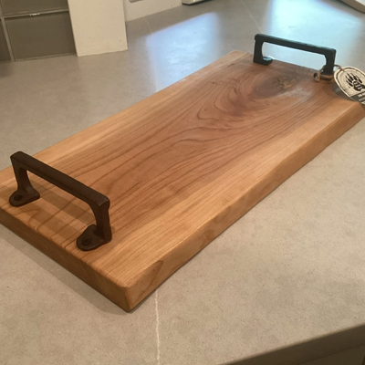A wooden tray with metal handles is sitting on a counter