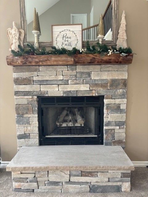 A fireplace with a wooden mantle and a stone wall