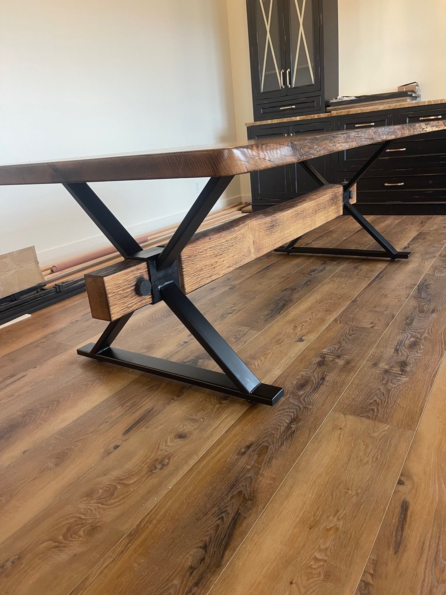 A wooden table with metal legs is sitting on a wooden floor in a room.