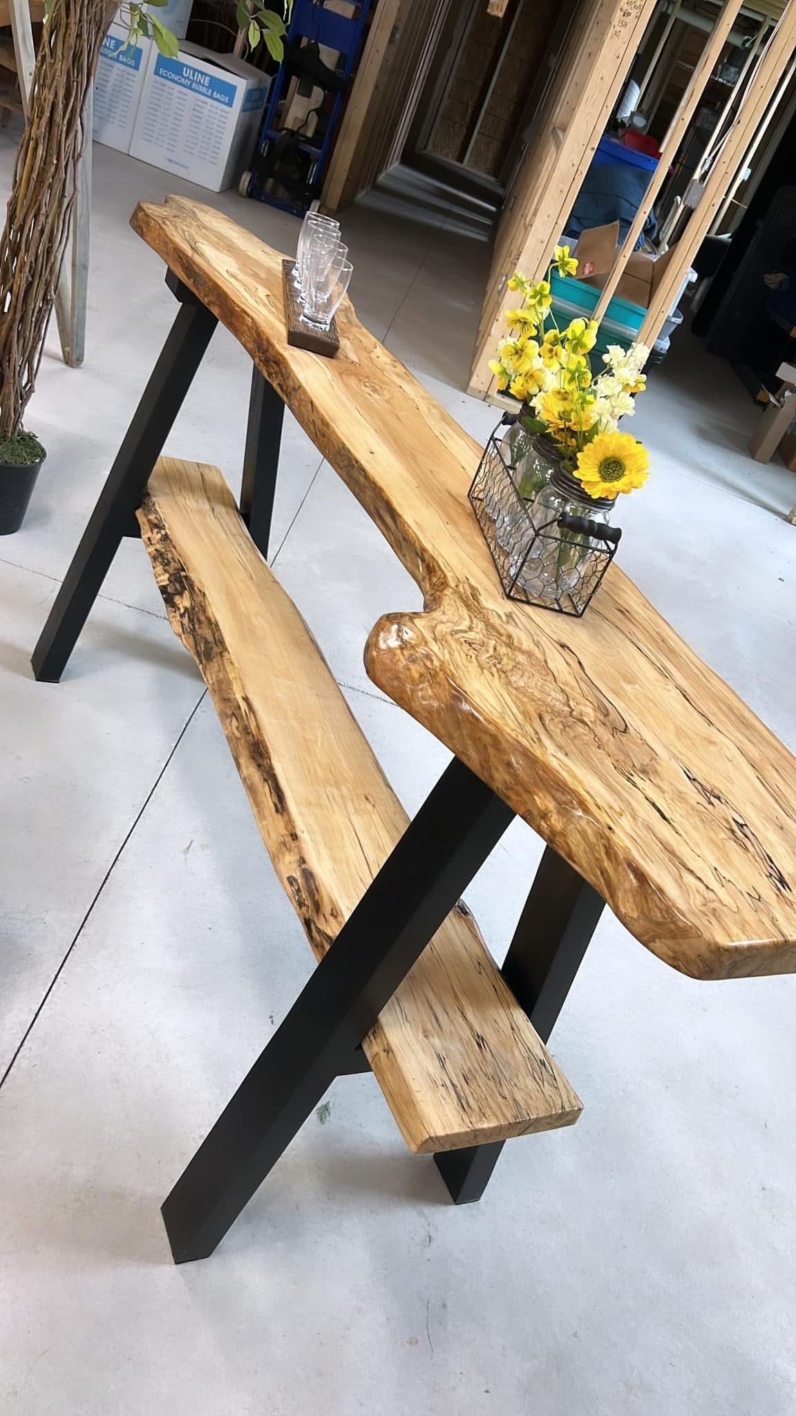 A wooden table with a vase of flowers on top of it.