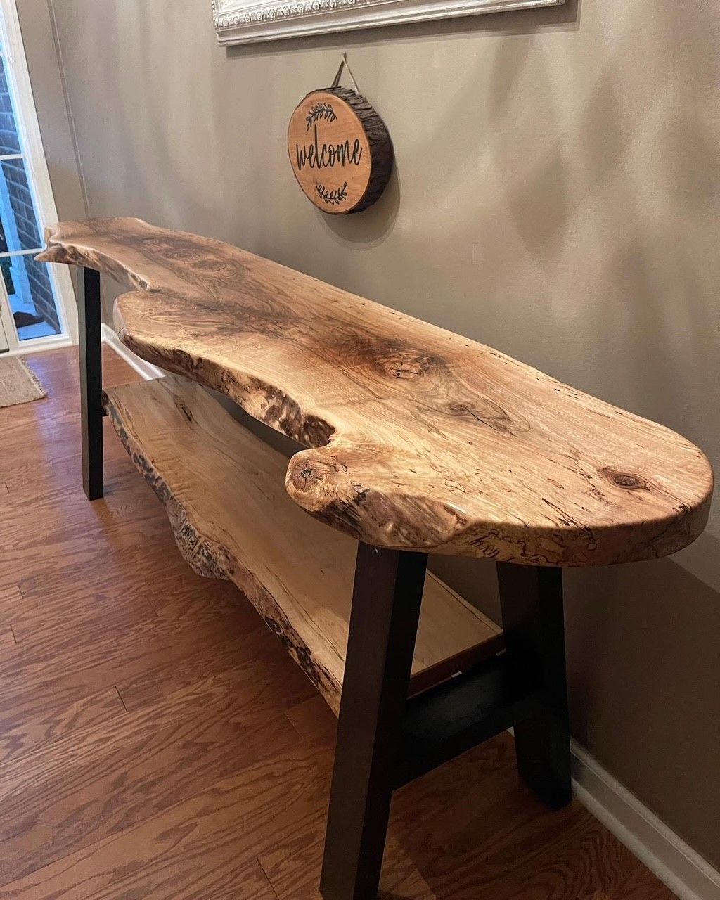 A large wooden table and chairs in a kitchen with a staircase in the background.
