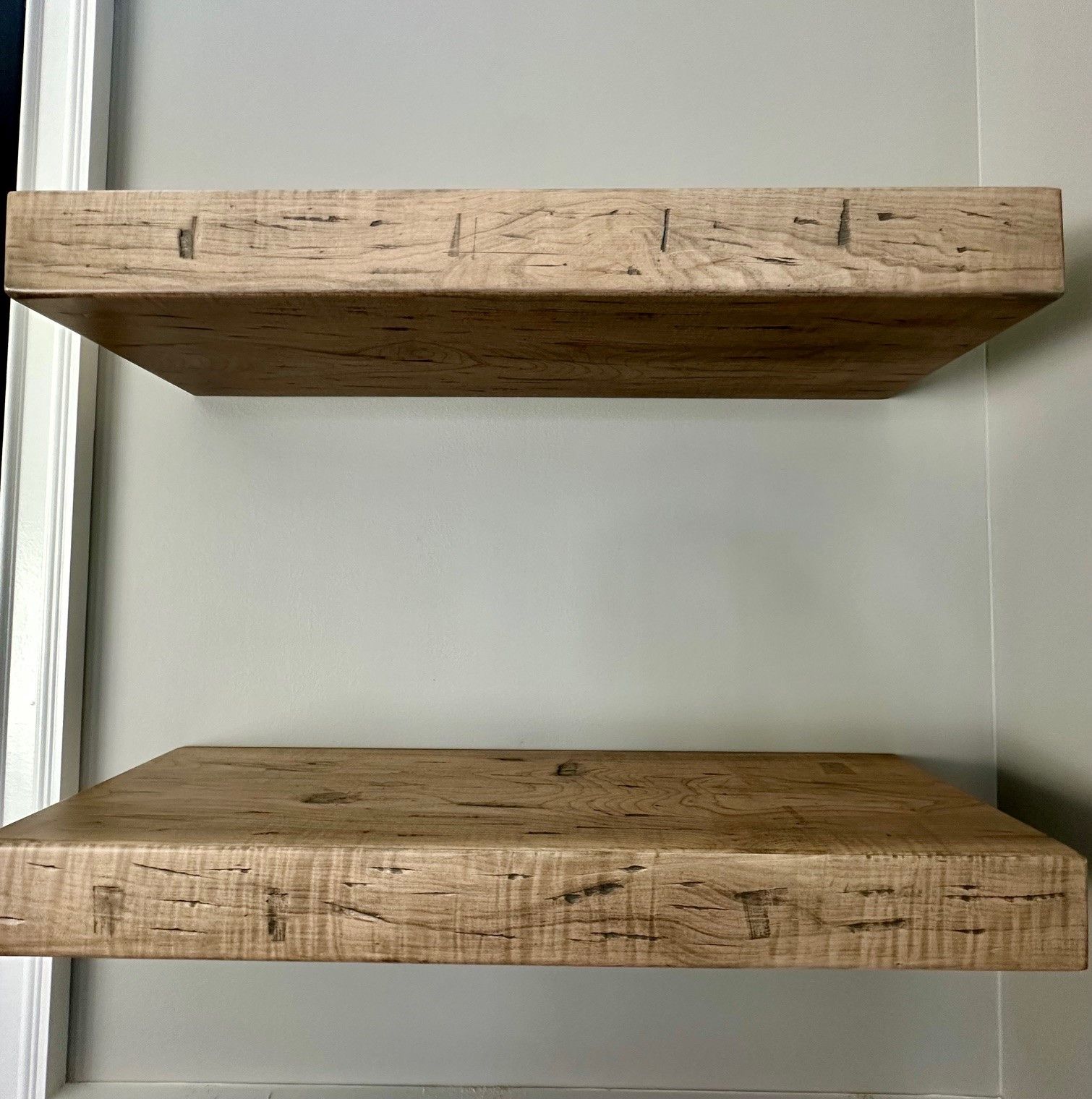 Two wooden shelves are hanging on a wall.