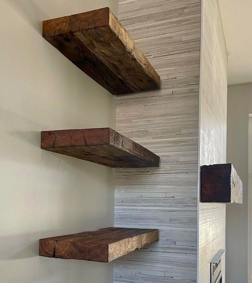 A living room with three wooden shelves filled with books and pictures.