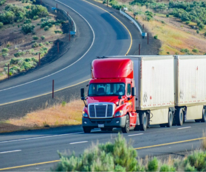 White semi-trailer backed into loading dock of a commercial building.