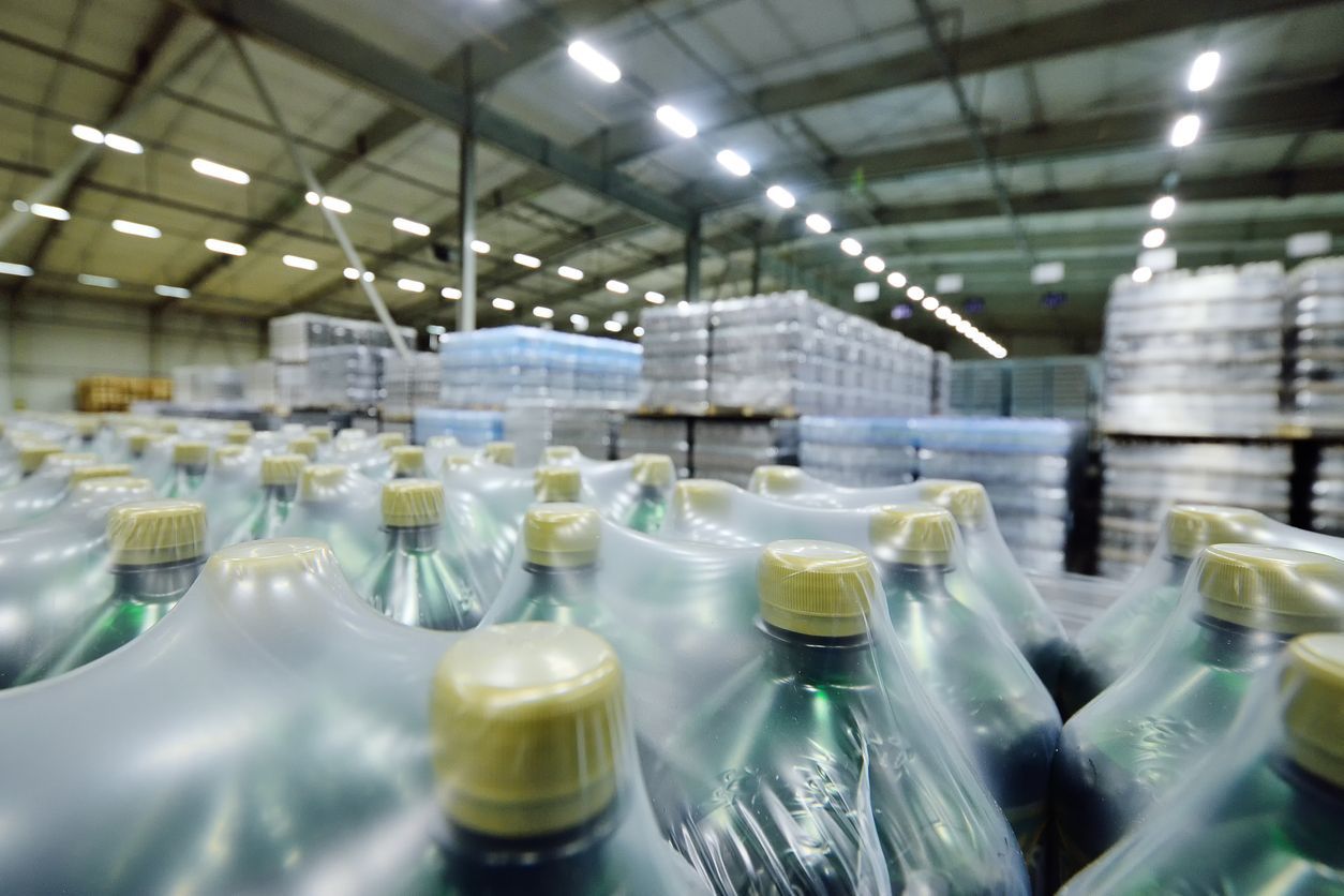 Bottled beverages in shrink wrap, stacked in a warehouse setting.