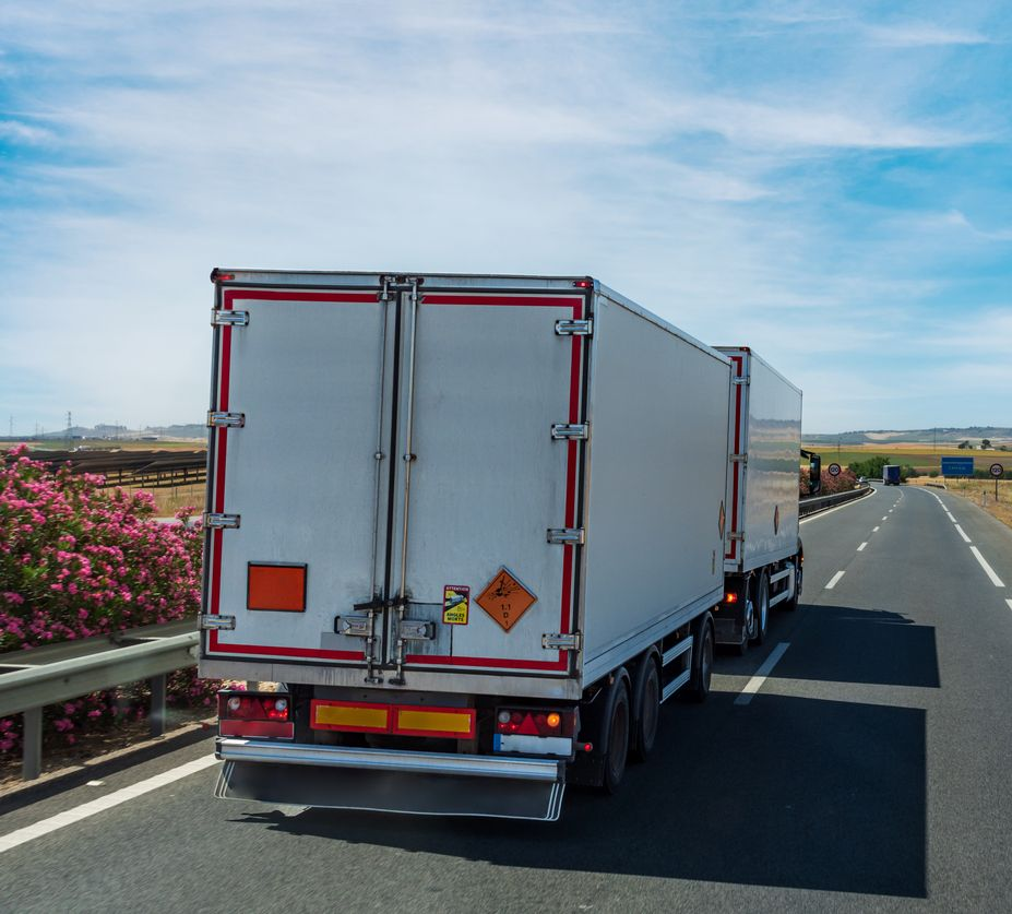 White semi-truck driving on a highway, transporting goods.