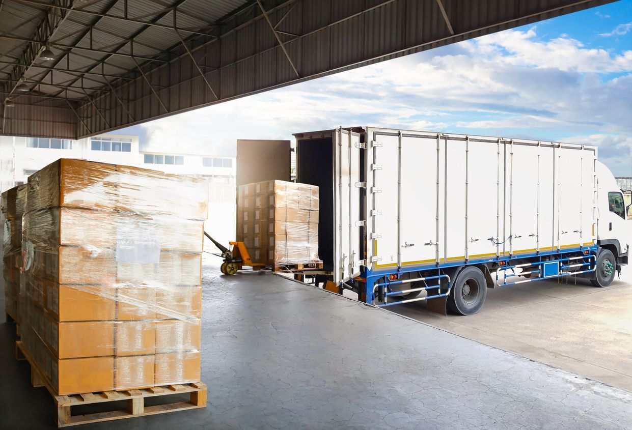 Truck being loaded with pallets of boxes inside a warehouse.
