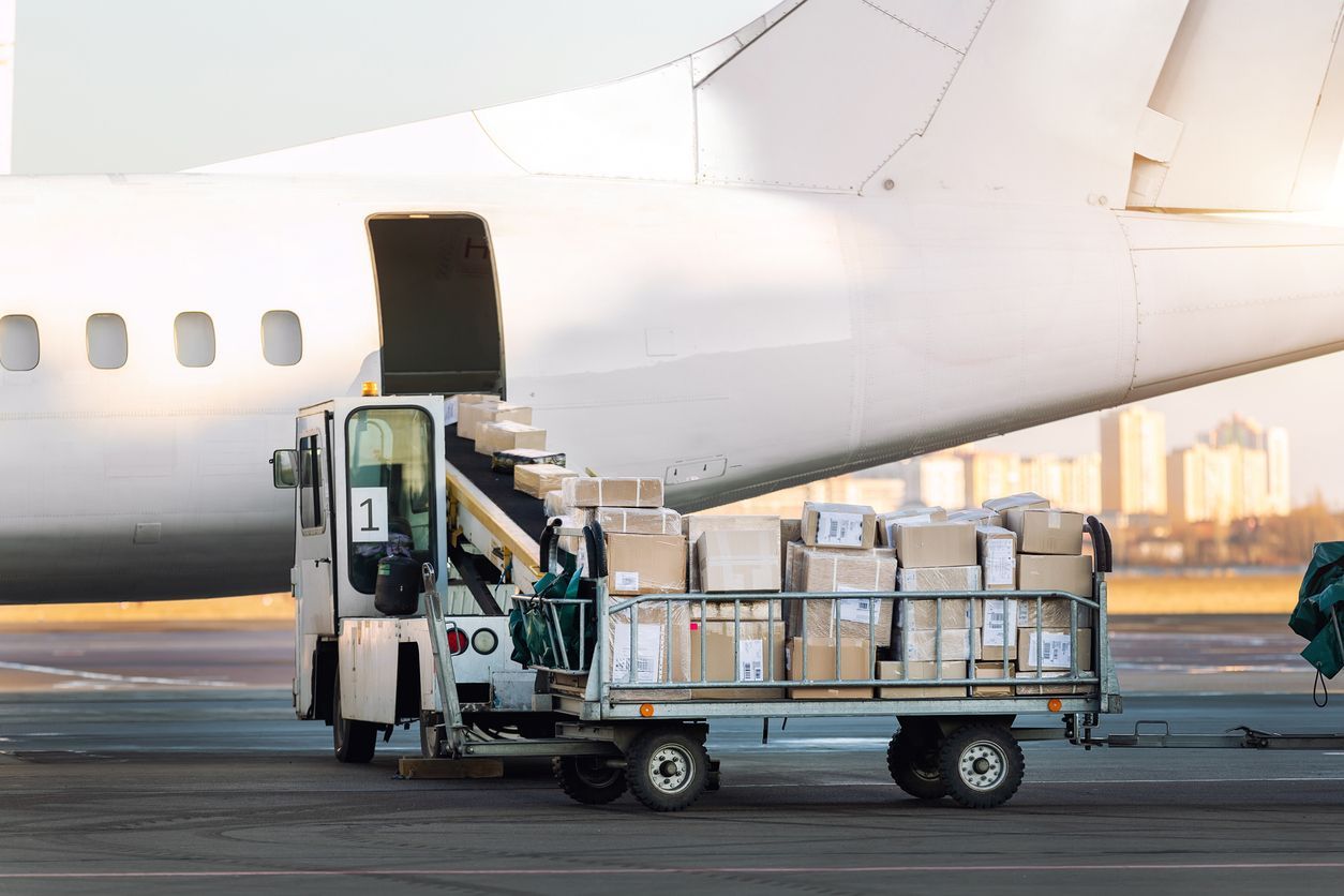 A cargo truck loading boxes into an airplane on a runway.