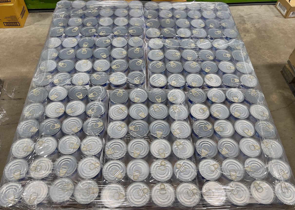 Pallet of canned goods wrapped in plastic; gray lids visible.