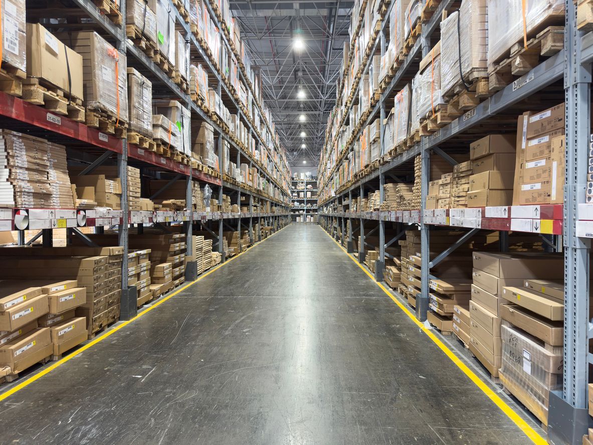 Warehouse interior with tall shelves stacked with cardboard boxes.