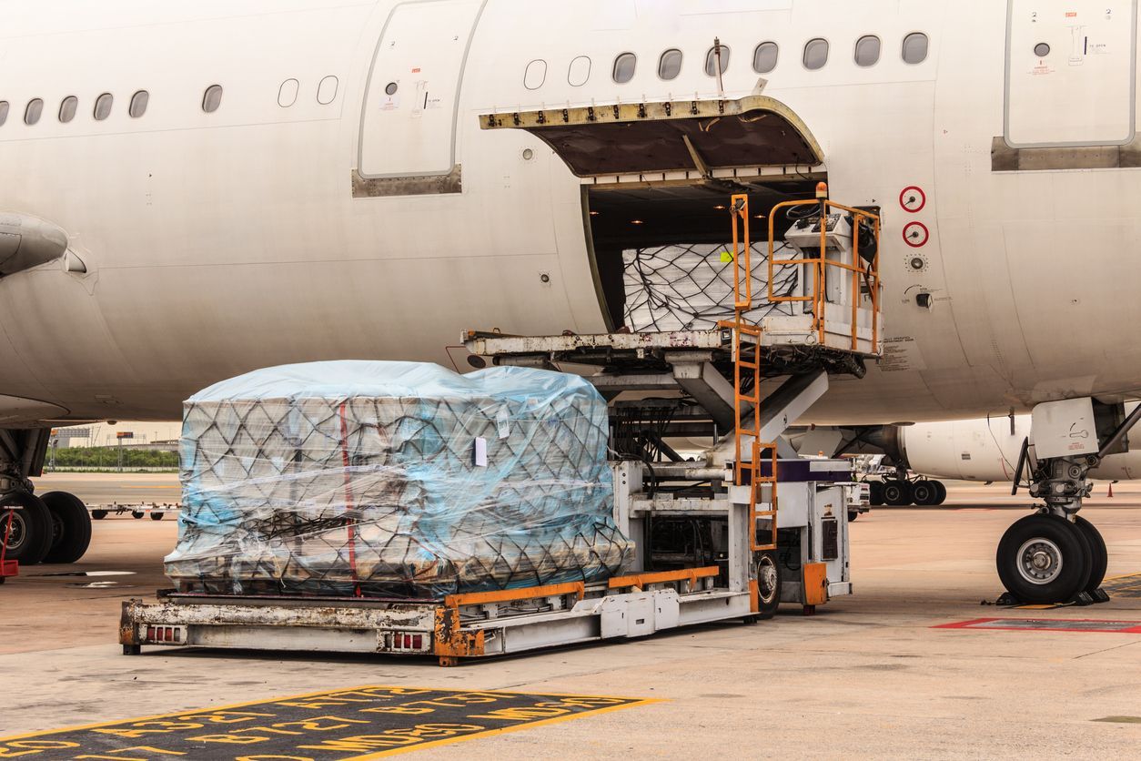 Cargo being loaded onto a large airplane via a lift at an airport.