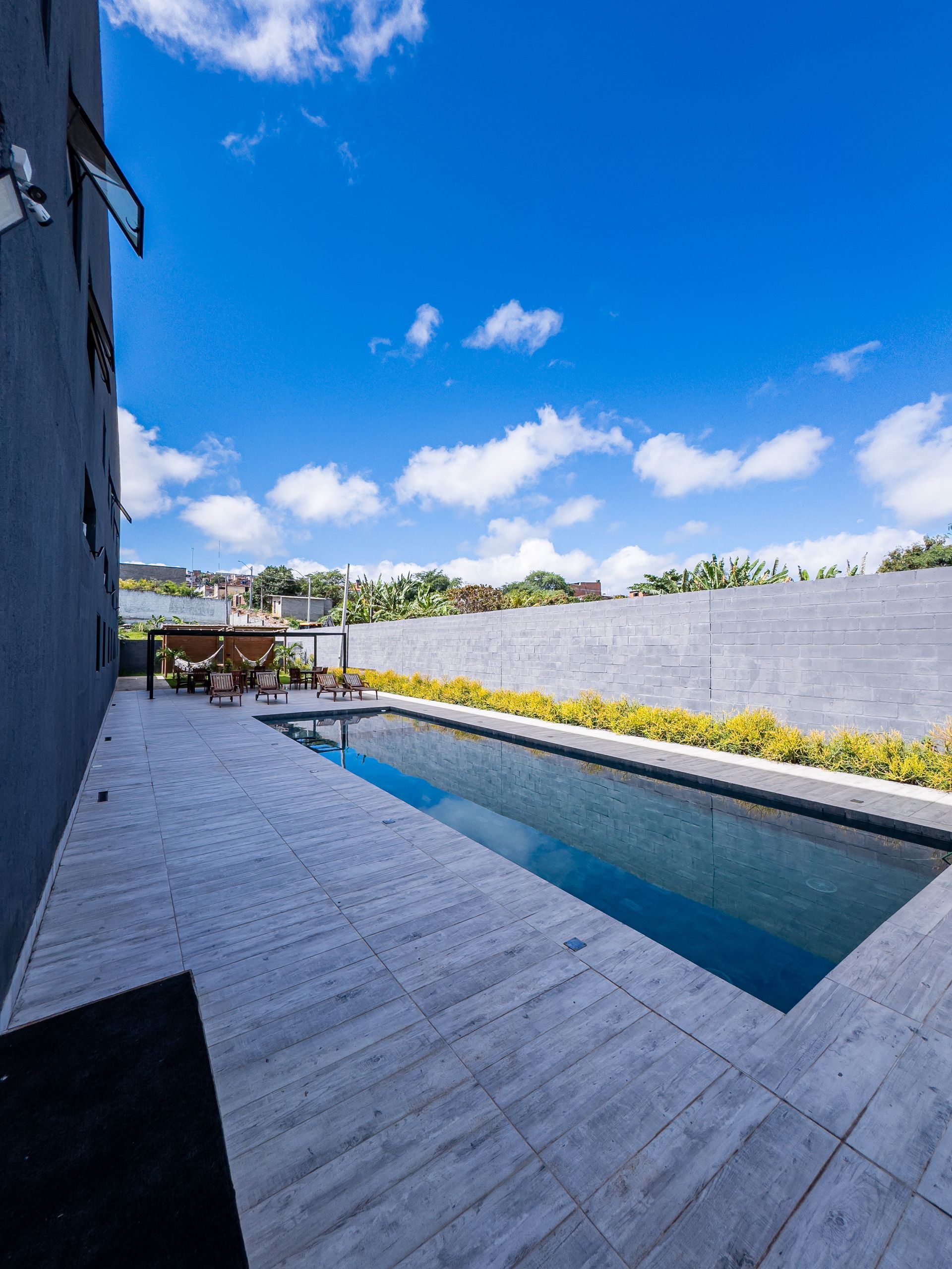 Piscina com água azul ao lado de um prédio em um dia ensolarado.