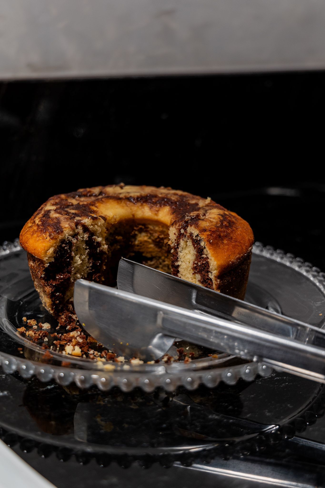 Bolo mármore em um prato de vidro com pinça; falta uma mordida.