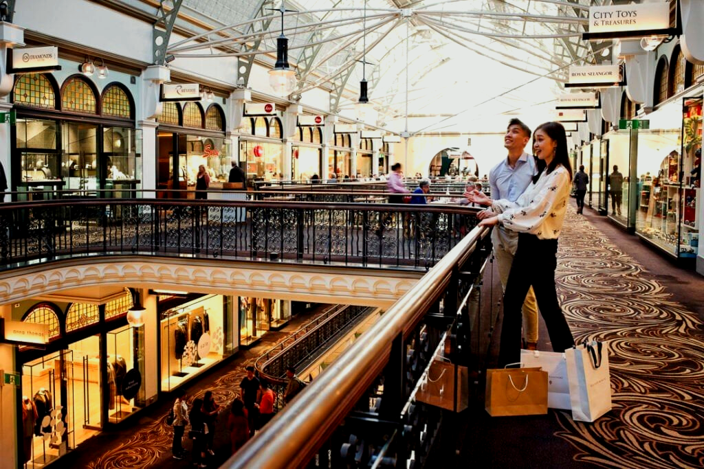 A man and a woman are standing on a balcony in a shopping mall.