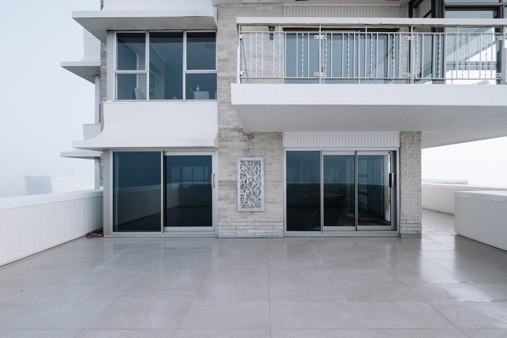 A large white house with a balcony and sliding glass doors.
